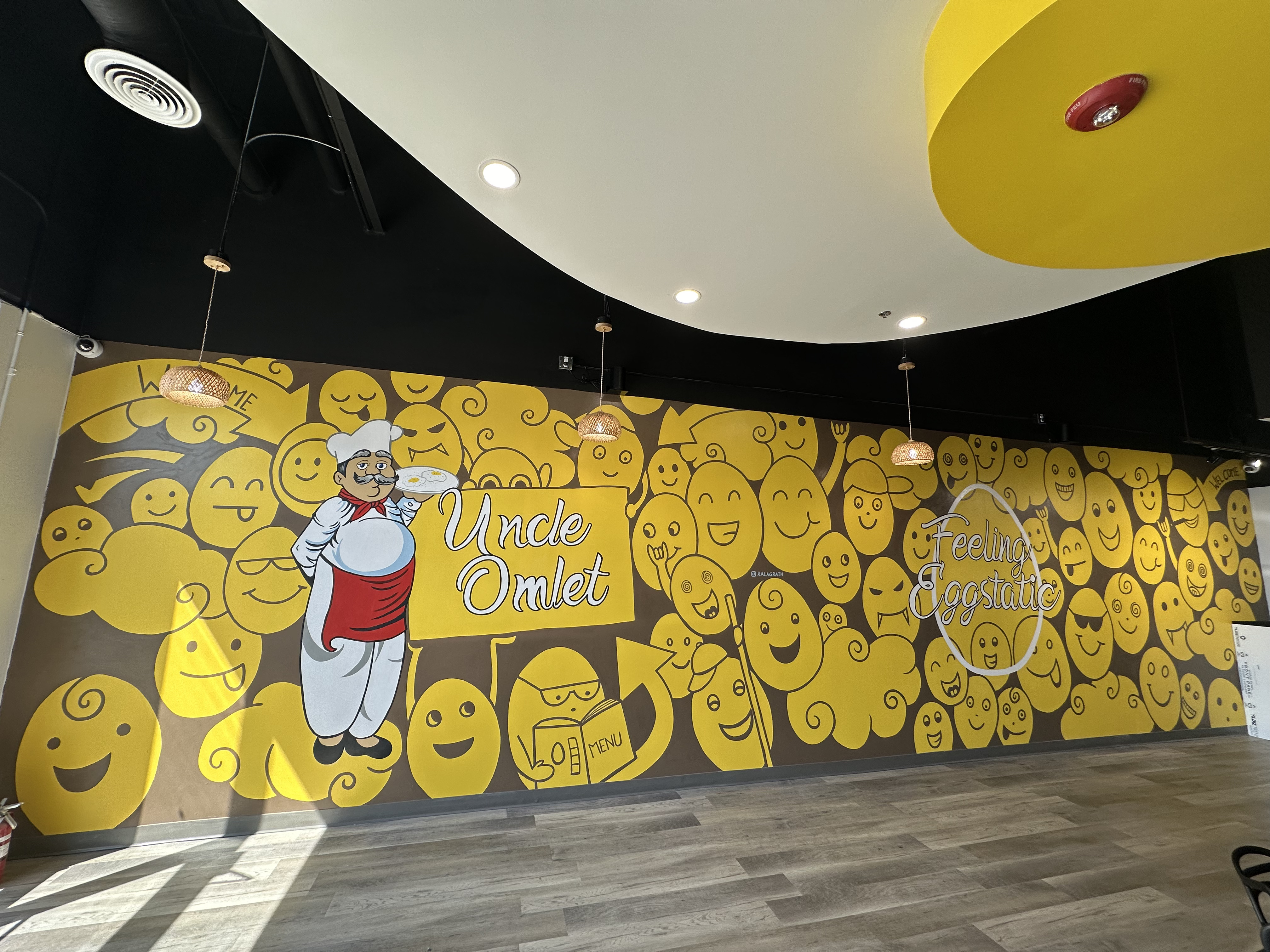 Wide shot of Uncle Omlet restaurant interior yellow and brown custom wall mural