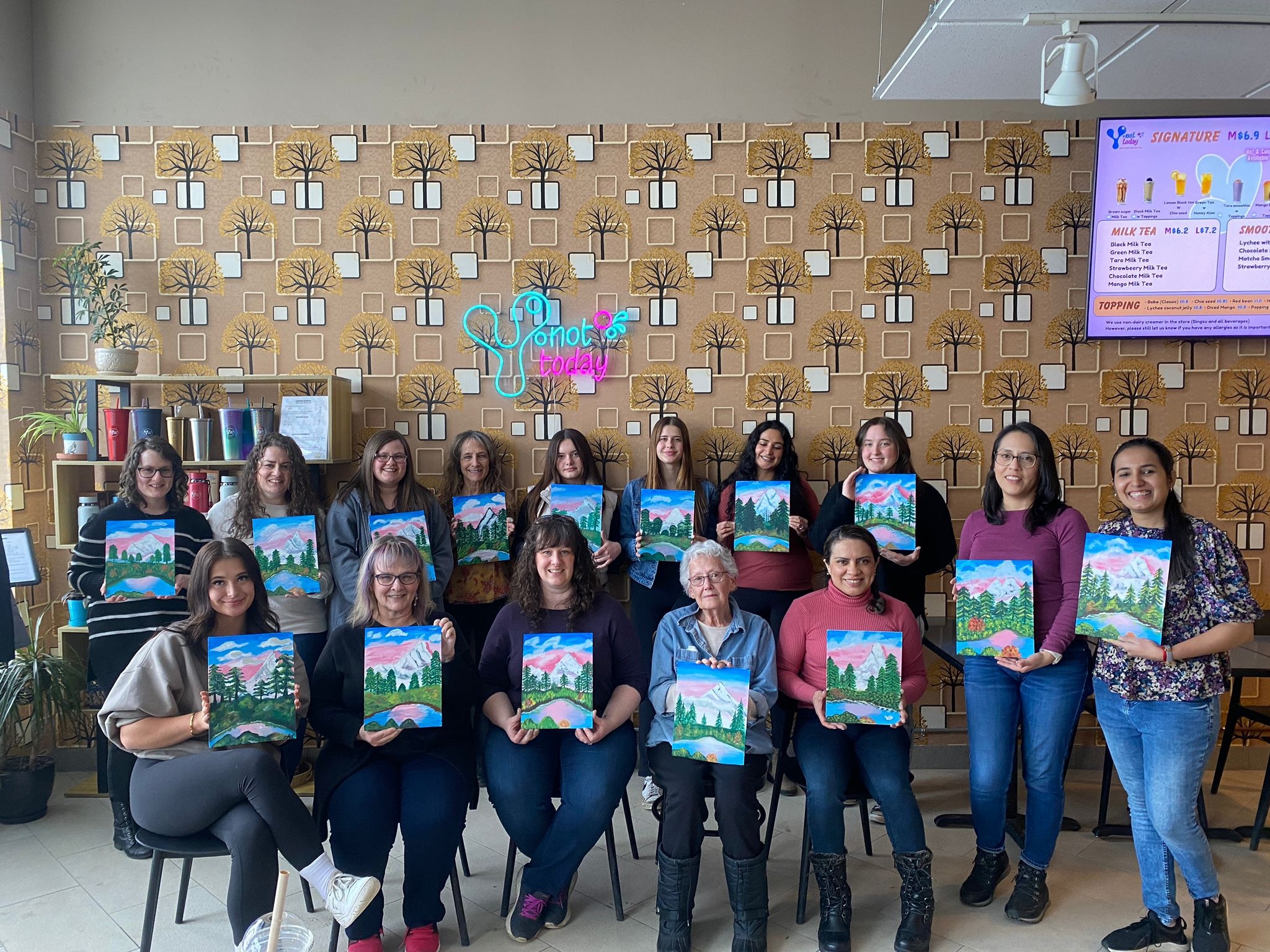 Large group of women holding up their mountain landscape canvas paintings