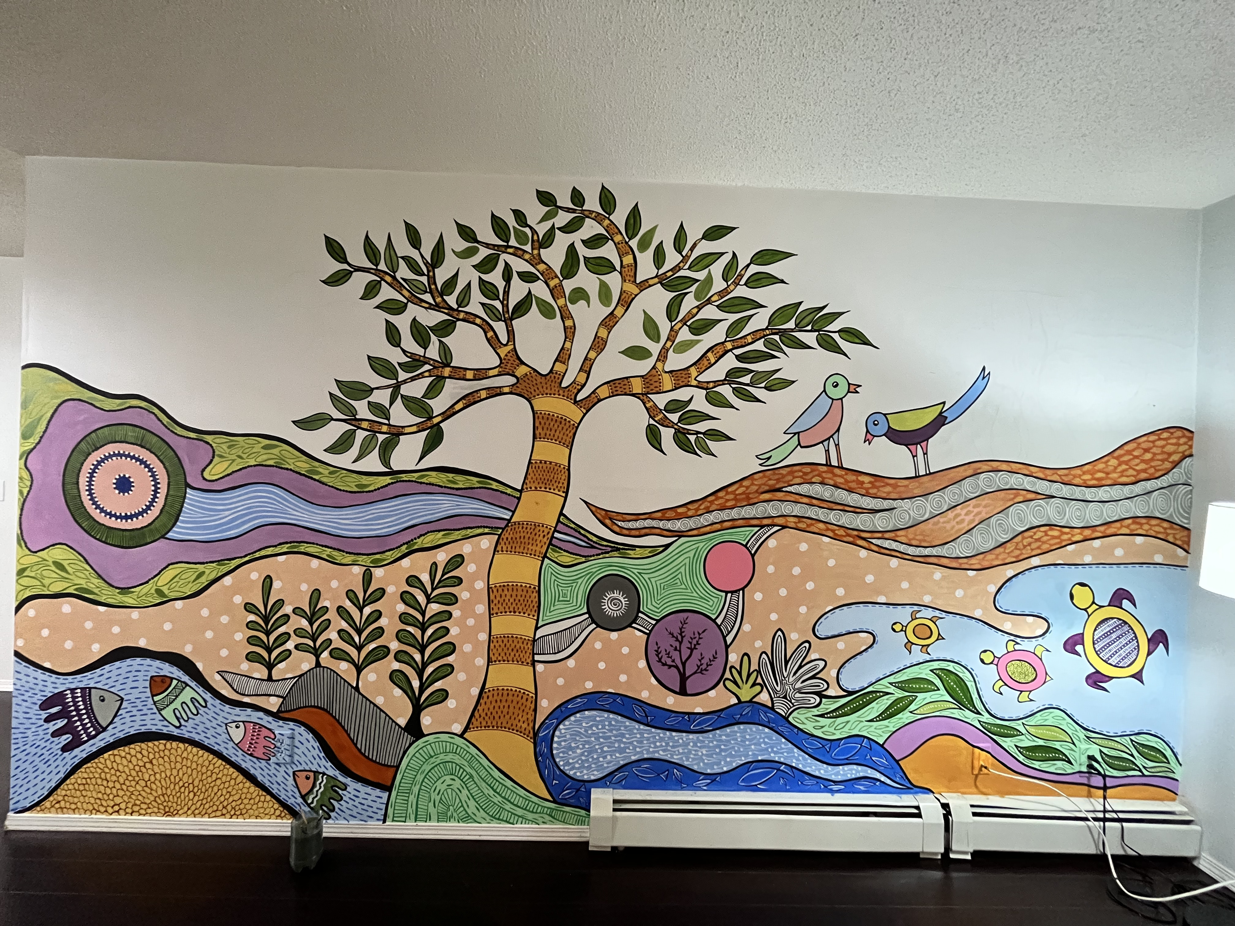 Wide shot of vibrant nature mural with tree, river, turtles, and birds